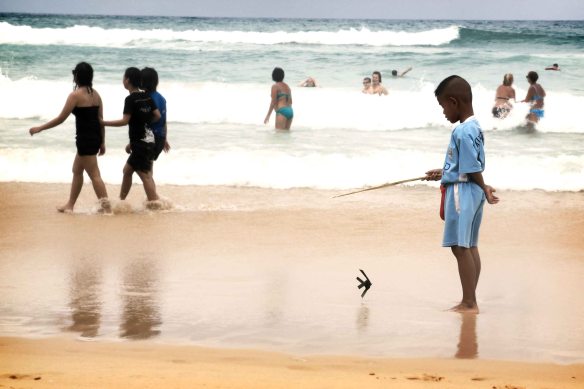 This kid was quietly playing with his toy fish whilst his parents were working hard to sell their ware on the beach